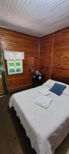 een slaapkamer met een bed met witte lakens en 2 ramen bij Pousada Florada na Serra - Apto 5 in Campos do Jordão