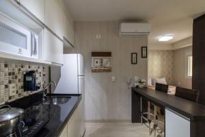 a kitchen with a black counter top and a refrigerator at 0406 - Studio Refúgio Cidade Maia in Guarulhos