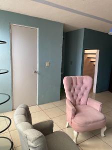 a living room with a pink chair and two chairs at Hermosa casa con dos habitaciones y dos baños in Cerro Gordo