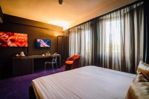 a hotel room with a bed and a desk at Plaza V Hotel in Târgu-Mureş