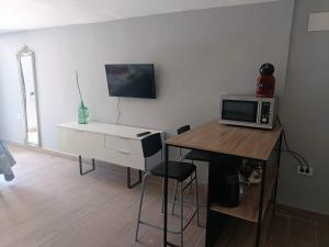 a room with a desk with a computer and a microwave at La Rueda, campo y playa en el Medano in El Médano
