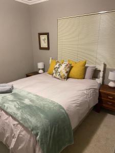 Un dormitorio con una gran cama blanca con almohadas amarillas. en Searle Cottage, en George