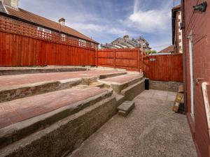 an empty courtyard with a red fence and steps at 3BR Haven Retreat in Wallasey with FREE Street Parking in Wallasey