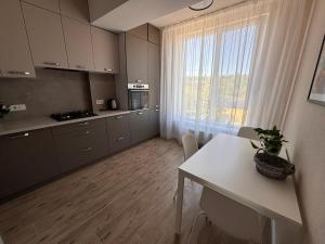eine Küche mit einem weißen Tisch und einem großen Fenster in der Unterkunft Milescu Residence 2 in Chişinău