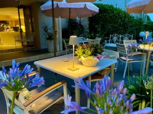 シルミオーネにあるHotel Alfieriの椅子とパラソル付きの花のテーブル