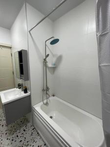 ein weißes Badezimmer mit einer Badewanne und einem Waschbecken in der Unterkunft Guest House NIMA in Kutaissi