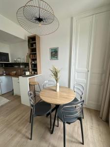 a dining room with a table and chairs and a chandelier at La Belle brise in Granville