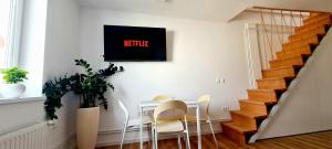 une salle à manger avec une table, des chaises et une télévision murale dans l'établissement Little Plaza Duplex, à Ljubljana