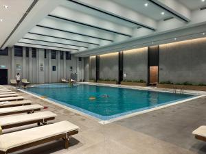 a large swimming pool in a building with chairs at Family Suite for 4 - 6 people! Direct access to Tashkent CITY MALL, Central Park, Hilton Hotel, Chorsu Bazaar! in Tashkent