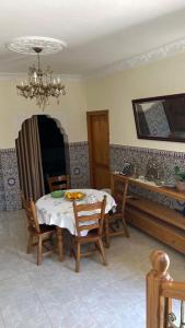 a dining room with a table and chairs and a chandelier at villa dans une ferme écologique in Asilah