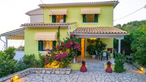 a yellow house with flowers in front of it at Caza Levantiera in Kalamitsi