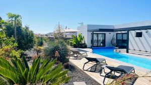 un patio trasero con piscina y sillas y una casa en Casa Carica with heated pool in Lajares, en Lajares