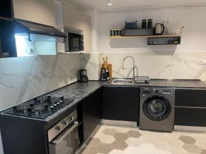 a kitchen with a stove and a washing machine at Rue de Paris - Plage Saint Germain - vue sur mer - in Aïn El Turk