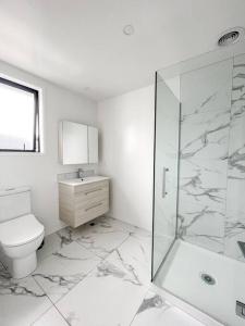 a white bathroom with a toilet and a shower at Hagley Park Townhouse in Christchurch