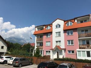 a pink building with cars parked in a parking lot at EMMA in Nová Lesná