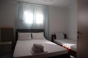 a bedroom with two beds with white sheets and a window at Apartments Bela in Paleo Tsifliki