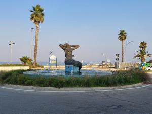 a statue of a woman sitting in a fountain with palm trees at La Sirenetta in Tortoreto Lido