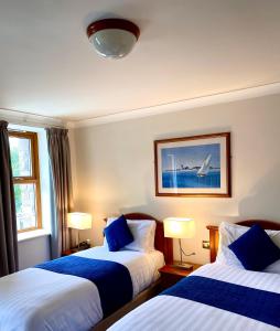 a hotel room with two beds with blue pillows at An Cruiscin Lan in Spiddal
