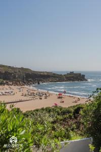 a beach with people on the sand and the ocean at São Lourenço Apt - Amazing terrace with Sea View in Ericeira