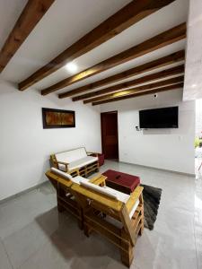 sala de estar con 2 mesas y TV de pantalla plana en Casa familiar RS, en Villa de Leyva