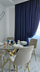 a dining room with a table with chairs and a blue curtain at Apartament Paris in Uniejow