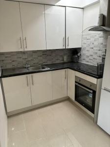 a kitchen with white cabinets and a sink and a stove at One bed Flat in Perivale
