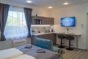 a bedroom with a bed and a desk and a kitchen at Heaven Apartment in Hajdúszoboszló