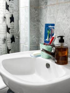 a white bathroom sink with a bottle of soap at Aliam Apartment in Novi Pazar