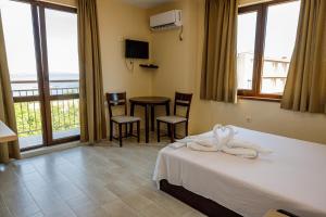 a hotel room with a bed and a table and chairs at Family Hotel Silitur in Ahtopol