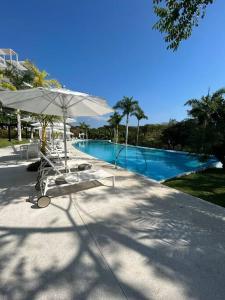 Higuera BlancaにあるDepartamento Sol y Mar Punta Mita, Beach Frontのスイミングプール(椅子、パラソル付)