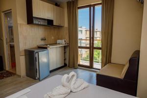 a room with a bed and a kitchen with a window at Family Hotel Silitur in Ahtopol