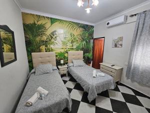 two beds in a room with a palm mural at Hostal Sevillana Costa in Chipiona