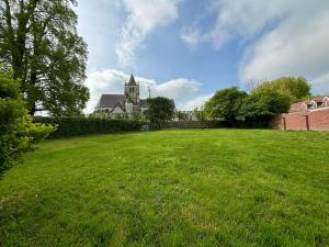 a large field of grass with a building in the background at Gîte des 6 tilleuls in Bomy