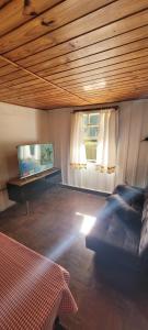 Un dormitorio con una cama y un televisor de pantalla plana. en Casa Violeta, en Campos do Jordão