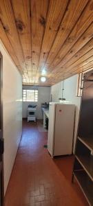 Una cocina con un refrigerador blanco y un techo de madera. en Casa Violeta, en Campos do Jordão