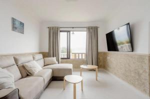 Una sala de estar blanca con un sofá y una mesa. en Serenity Haven, en Icod de los Vinos