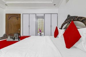 a bedroom with a large white bed with red pillows at Super Hotel O Alpine Glow Crest in Hyderabad