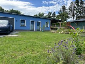 a blue house with a car parked in a yard at Villa Frankenstein - Deluxe Ferienwohnung mit Ladestation E-Auto & E-Bike in Lancken-Granitz