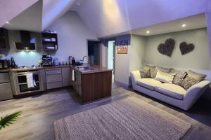 a living room with a couch and a kitchen at Luxury 1 Bed Coach House in Huddersfield