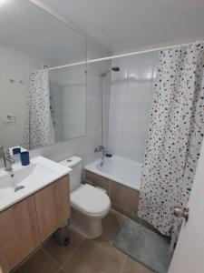 Un baño con inodoro y cortina de ducha. en Apartamento a pasos del Mar, en La Serena