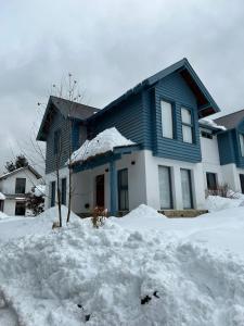 a blue house with a pile of snow in front of it at Sombra Verde - Alojamiento Turistico in Villa La Angostura