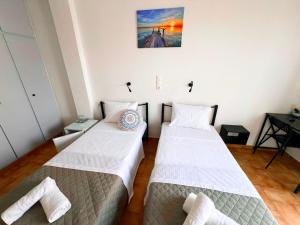 two beds in a room with white sheets at Hotel Liliana in Agia Marina Aegina