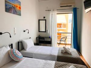 two beds in a room with a balcony at Hotel Liliana in Agia Marina Aegina