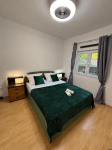 a bedroom with a bed with a green blanket and a window at Apartment Maribel in Tribanj-Krušćica