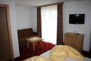 a hotel room with a bed and a couch and a television at Hotel Garni Dorfblick in Sankt Anton am Arlberg