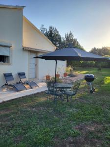 een grill en een tafel en stoelen onder een parasol bij Maison jumelée clôturée in Linguizzetta