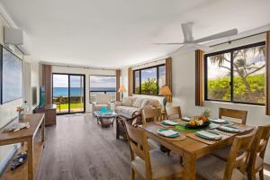 ein Wohnzimmer mit einem Tisch, Stühlen und Meerblick in der Unterkunft Poipu Shores 107A in Koloa