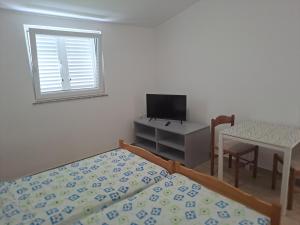 a bedroom with a bed and a table and a television at Apartman Put 2 in Baška