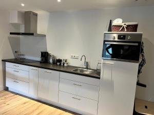 a white kitchen with a sink and a microwave at Appartement Plein 1944 in Nijmegen