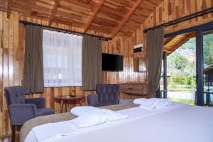 a bedroom with two beds and two chairs and a television at Ruby Bungalow Alanya in Yaylalı